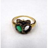 A gold, emerald and diamond ring in a twin hearts and bow design,