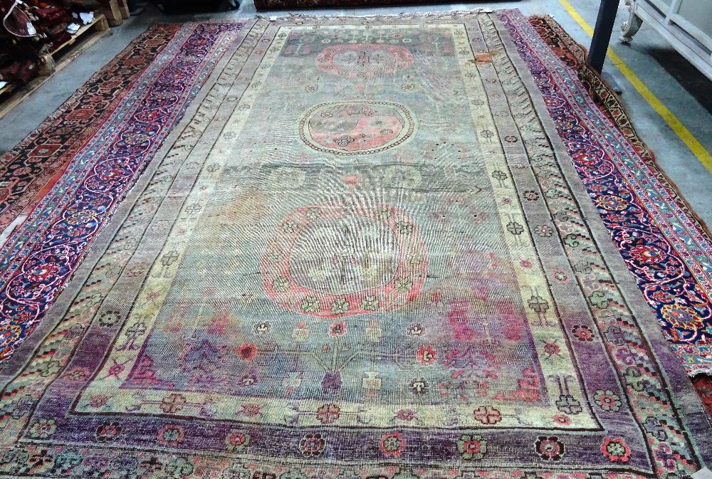 A Khotan carpet, ,the faded purple field with three bold roundels,