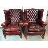 A pair of George III style mahogany framed wingback armchairs with red leatherette button back
