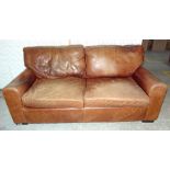 A brown aniline leather three seater sofa, raised on wooden square feet, 196cm wide.