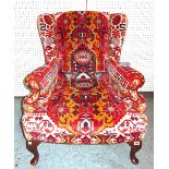 A 20th century mahogany framed wingback armchair with Kelim upholstery on tapering cabriole