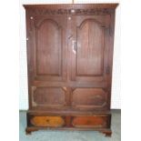 An 18th century style oak double wardrobe with panelled doors over two drawer base on bracket feet,