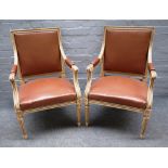 A pair of Louis XVI style cream painted open armchairs on tapering fluted supports,