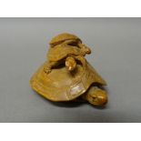 A Japanese wood netsuke of a tortoise and young, inlaid eyes to the adult and one of the young,