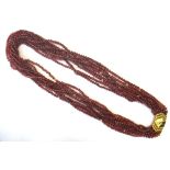 An eight row necklace of garnet beads, on a gold and diamond set single stone clasp,