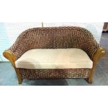 A 20th century mahogany framed rattan two seat sofa on block supports, 109cm wide x 179cm high.