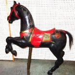 An early 20th century black painted composite carousel horse on twisted brass column stand,