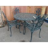 A 20th century green painted metal circular garden table with vine decoration and a set of four