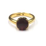 An 18ct gold ring, claw set with a circular cut garnet, ring size K, gross weight 4.7 gms.