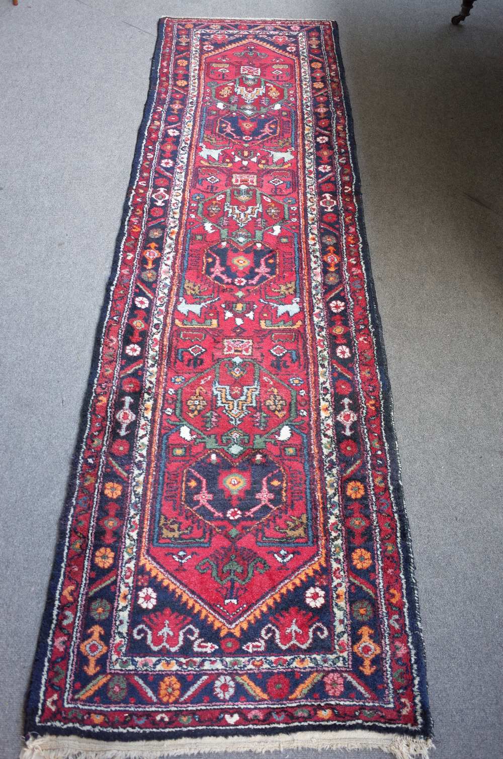 A North West Persian runner, the madder field with three stylised medallions, black spandrels,