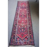 A North West Persian runner, the madder field with three stylised medallions, black spandrels,