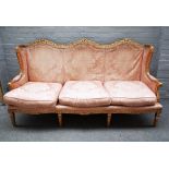 A Louis XVI style gilt framed sofa, with ribbon tied triple hump back, on fluted square supports,