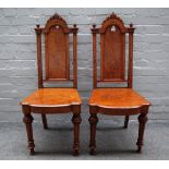 A pair of Victorian pollard oak hall chairs with solid arch back and seat on tapering fluted