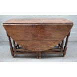 A 17th century oak gate leg dining table on baluster supports united by block stretchers,