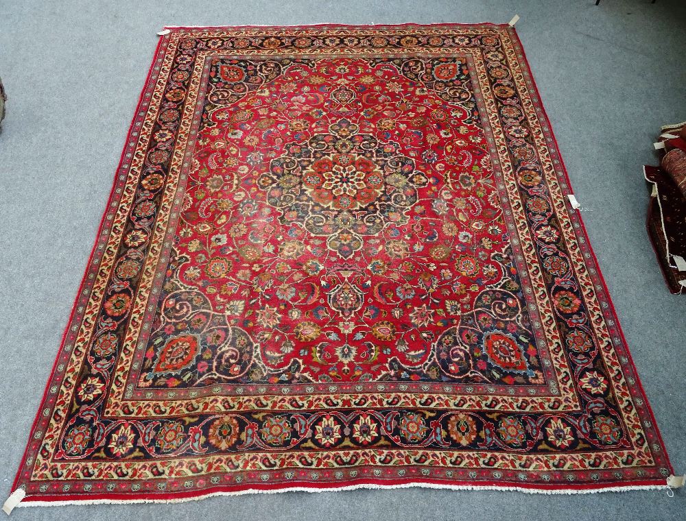 A Mashad carpet Persian, the madder field with a bold dark indigo rosette medallion,