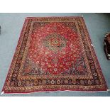 A Mashad carpet Persian, the madder field with a bold dark indigo rosette medallion,