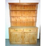 An early 20th century and later pine dresser with enclosed three tier plate rack over a pair of