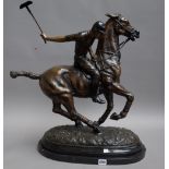 A modern patinated bronze polo player, modelled sitting on his pony, mallet raised,
