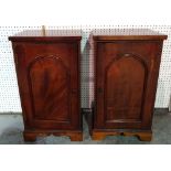 A pair of 20th century mahogany bedside cupboards with arch panel doors on bracket feet,