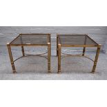 A pair of mid-20th century lacquered brass and smoked glass occasional tables, on turned supports,