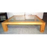 A 20th century oak coffee table with inset glass top on block supports, 152cm wide x 39cm tall.