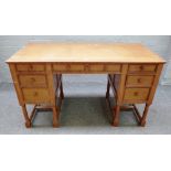 An early 20th century oak writing desk with seven drawers about the knee on turned supports,