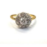 A gold and diamond cluster ring, claw set with the principal cushion shaped diamond at the centre,