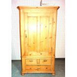 A 20th century pine single wardrobe over two short and one long drawers on bun feet,