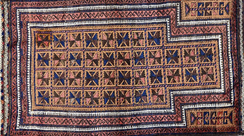 A Beluchistan prayer rug, the pale brown mehrab with squared sections of single flowerheads,