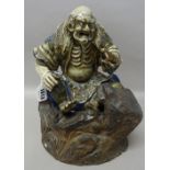 A Japanese Satsuma figure of Gama Sennin, Meiji period, seated with a toad in his left hand,