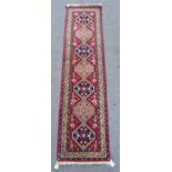 A South Persian runner, the madder field with seven diamonds, an ivory border, 295cm x 76cm.