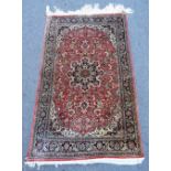 A silk rug, central stylised star medallion within pink red field, allover floral decoration,