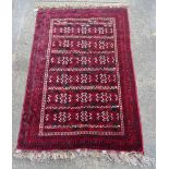 An Afghan Turkeman carpet, the deep red field with six rows filled with stepped geometric forms,