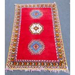 A Moroccan carpet, North African, the plain madder field with three single medallions,