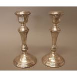 A pair of silver table candlesticks, each of circular form, decorated with ridged bands,