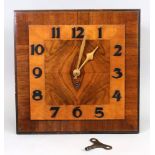 An Art Deco figured walnut and satinwood wall timepiece, 33cm square, with key (2).