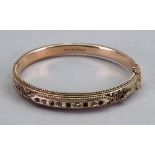 A 9ct gold, diamond and red gem oval hinged bangle,