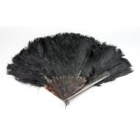 A black Ostrich feather fan, early 20th century, with tortoiseshell sticks, 41cm long.