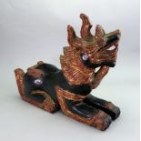 A South East Asian carved and painted wood figure of a recumbent temple lion, 20th century,