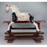 A Victorian wooden rocking horse, painted black and white, on a stained pine trestle base,