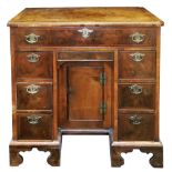 An early 18th century walnut feather and crossbanded kneehole desk,