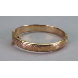A 9ct gold hinged bangle, the front engraved with a scrolling foliate design, 13.