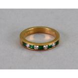 An 18ct gold, emerald and diamond half eternity ring the four round brilliant cut diamonds channel