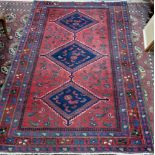 A Hamadan rug, with three lozenges, on a red ground, 204 x 133cm.