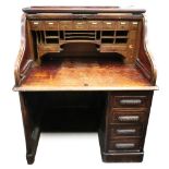 An early 20th century oak roll top desk, of panelled construction,