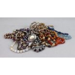 A collection of costume jewellery, comprising; a shell necklace, two blue strands of beads,