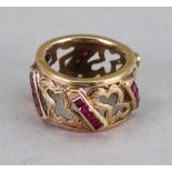 A gold and ruby ring, six rows of four step cut rubies channel set between gold openwork design,