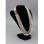 A triple-row necklace of graduated cultured pearls, on a square sapphire and diamond set clasp,