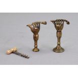 Two novelty brass pipe tampers, 18th/19th century, each cast as a raised hand holding a pipe, 5.