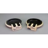 A pair of Art Deco white and black bakelite ashtrays, inscribed 'R.M.S. Queen Mary', 17.5cm across.